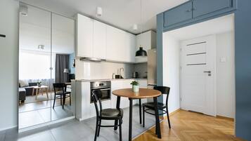 A modern kitchen with white cabinets, a round wooden table, and black chairs.