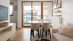 Una sala de estar moderna con comedor, suelo de madera y un ventanal con persianas.