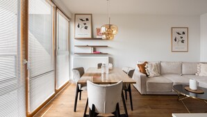 Una sala de estar moderna con una mesa de comedor de madera, un sofá blanco y una lámpara colgante.