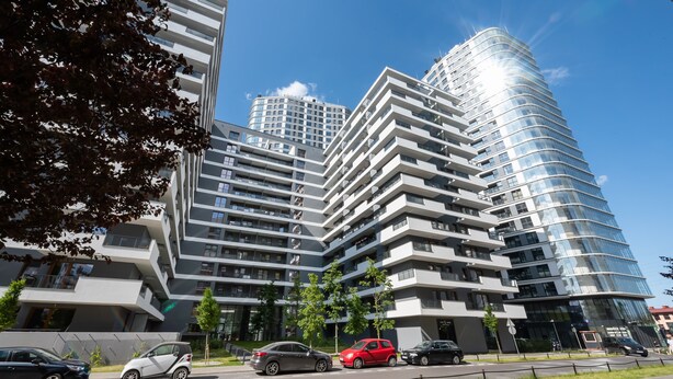Un edificio moderno de varios pisos con balcones y fachada de vidrio curvo.