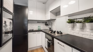 A modern kitchen with white cabinets, a black countertop, and a stainless steel refrigerator.
