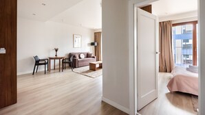 A modern hotel room with a wooden floor, a sofa, a small table, and a bed. - Magazynowa Classy Apartment (Warszawa)