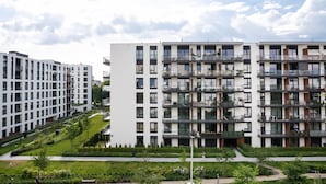 A modern multi-story residential building with balconies, a landscaped courtyard, and a clear sky. - Mokotów Serenity Premium Apartment (Warszawa)