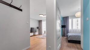 Ein modernes Schlafzimmer mit einem Bett, einem Nachttisch und einer Lampe. Ein Flur führt zu einem weiteren Raum mit einem Fernseher und einer Lampe.
