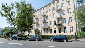 Um edifício residencial com vários andares, varandas, área de estacionamento e um ciclista de bicicleta.
