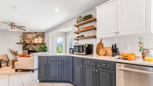 A modern kitchen with dark cabinets, a stone fireplace, and a view of mountains.