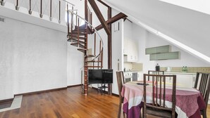 Une pièce spacieuse avec un escalier en bois, une table à manger avec des chaises et un coin cuisine.