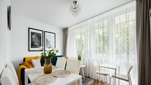 Un comedor moderno con una mesa blanca, sillas y un jarrón con flores.