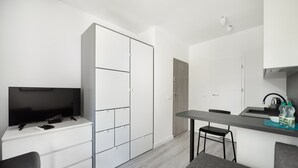 A modern, compact living space with a kitchenette, a flat-screen TV, a dining area, and a seating area.
