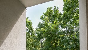 A balcony with a view of a lush green park and trees.