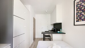 A modern hotel room with a bed, a desk, and a wardrobe.