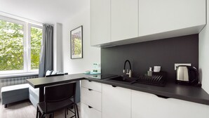 A modern kitchen with a black countertop, white cabinets, a built-in sink, and a kettle.