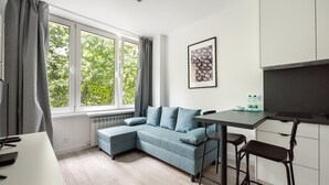 Ein modernes Zimmer mit grauem Sofa, einem Esstisch und einer Küchenzeile.
