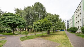 En park med anlagte stier, træer og en bygning med mange vinduer og altaner.