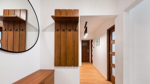 A hallway with wooden flooring, a wooden bench, and a wall-mounted coat rack.