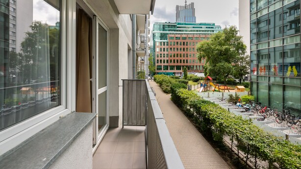 A balcony with a view of a cityscape, including modern buildings and a playground.