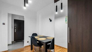 A modern dining area with a dark wooden table, black chairs, and a light-colored floor.