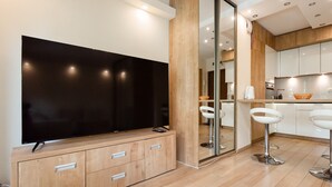 Eine moderne Küche mit großem Flachbildfernseher, Holzschränken und weißen Barhocker.