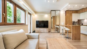Ein modernes Wohnzimmer mit einer Couch, einem Fernseher und einer Küchenzeile mit Bar.