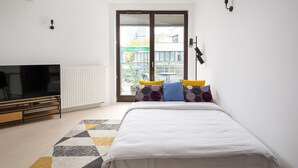 A bedroom with a bed, a TV, and a window with blinds.