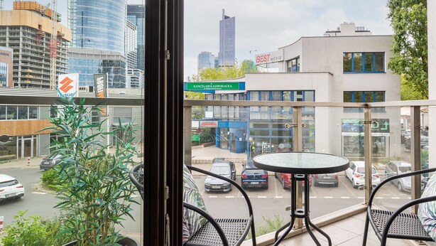 A balcony with a view of a cityscape, including a building with a sign that reads "KANCELARIA ADWOKA."