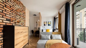 A modern living room with a brick wall, a sofa, a wooden cabinet, and a dining area. - Woronicza 80 Modern Studio (Warszawa)