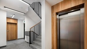 A modern interior with a staircase, elevator, and wooden paneling. - Woronicza 80 Modern Studio (Warszawa)