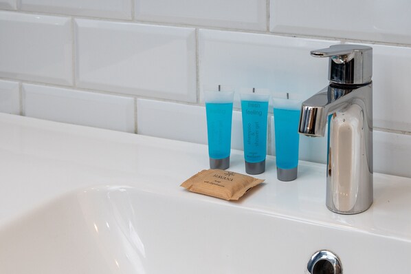 A bathroom sink with a chrome faucet, three blue bottles, and a brown paper bag labeled "Havana."