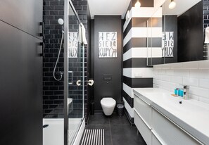 Features a sleek glass-enclosed shower, white sink, and black toilet.