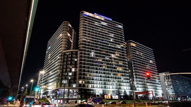 Um hotel com vários andares e design moderno, com uma placa chamativa no topo.
