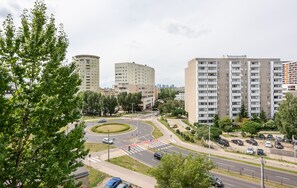 A multi-story residential building with a central roundabout, surrounded by greenery and other buildings.