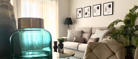 Una sala de estar moderna con un sofá, una mesa de centro de vidrio y un gran jarrón decorativo.
