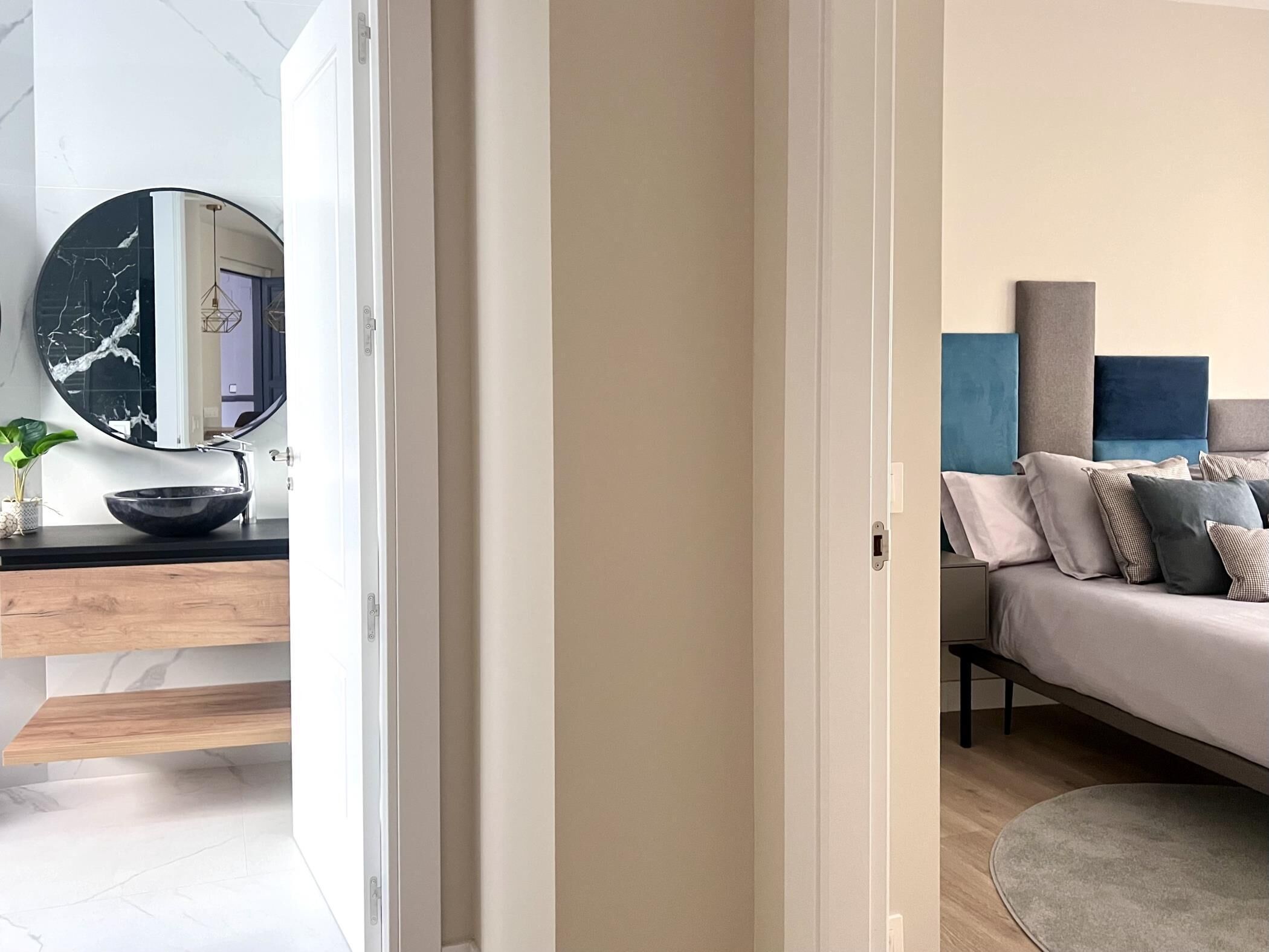 A modern bedroom with a bed, bedside table, and a large mirror.