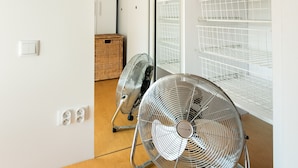 A modern, minimalist room with two standing fans, a wooden floor, white walls, and a large mirror. - Spiska Standard Studio (Warszawa)