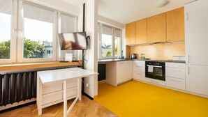 A modern kitchen with white cabinets, a black oven, and a yellow floor. - Spiska Standard Studio (Warszawa)
