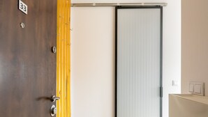 A hotel room with a wooden door marked '33', a sliding glass door, a yellow floor, and a blue mat. - Spiska Standard Studio (Warszawa)
