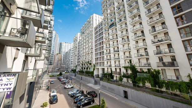 A high-rise residential building with multiple balconies, a parking lot, and a clear blue sky. - Varsovia Comfort 204 (Warszawa)