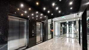A modern elevator area with metallic and glass doors, a polished marble floor, and recessed ceiling lighting. - Varsovia Comfort 204 (Warszawa)