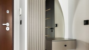A modern interior with a wooden door, a vertical panel, a mirrored wall, and a built-in bench with a drawer. - Varsovia Comfort 204 (Warszawa)