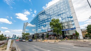 A modern glass building with a large entrance and signage for a sushi restaurant. - Varsovia Comfort 204 (Warszawa)