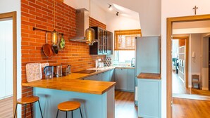 Una cocina moderna con pared de ladrillo, vigas de madera y una isla central con taburetes de bar.