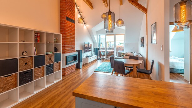 Una cocina moderna con encimeras de madera, pared de ladrillo y lámparas colgantes.