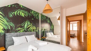 Un dormitorio con una cama grande, una mesita de noche, un espejo y un mural en la pared.