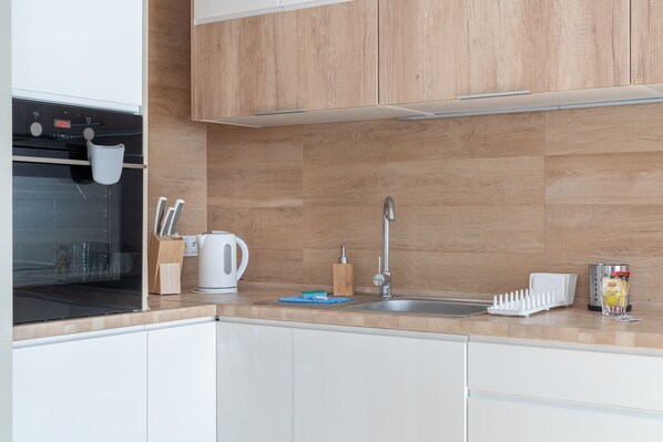 A modern kitchen with wooden cabinets, a stainless steel sink, and a built-in oven.