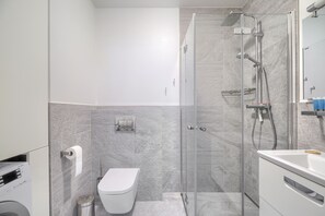Un baño moderno con cabina de ducha de vidrio, inodoro y lavamanos.