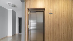 An elevator with a wooden panel wall, a floor number sign, and a no-smoking sign. - Warta River Comfort Apartment (Poznań)