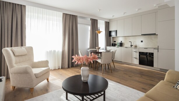 A modern living room with a sofa, a round coffee table, and a dining area with chairs and a table.