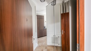 A hallway with a wooden door, a white radiator, and a kitchen area in the background.