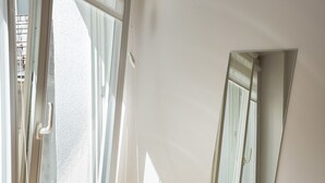 Ein Zimmer mit Schreibtisch, Stuhl und einem großen Fenster mit Vorhängen.