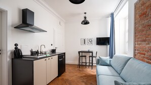 A compact living space with a kitchenette, a sofa, a dining area, and a TV mounted on the wall. - Metro Wileński Varsovia Studio #2 (Warszawa)